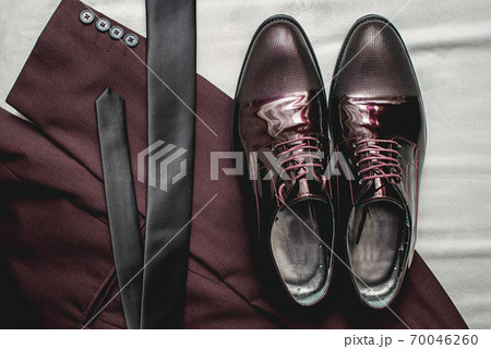 Suit, necktie, leather shoes on a white textile. Grooms wedding morning. Close up of modern man accessories Suit, necktie, leather shoes on a white textile. Grooms wedding morning. Close up of modern man accessories 70046260