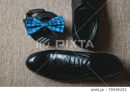 Blue bow tie, leather black shoes and belt. Grooms wedding morning. Close up of modern man accessories 70046262