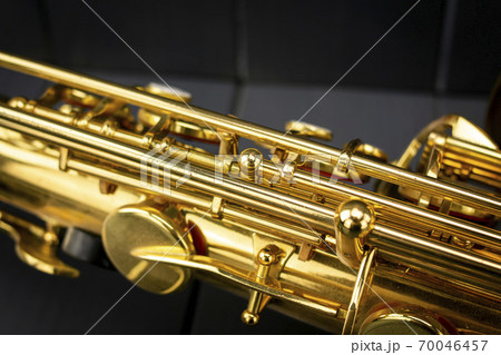 Keys and rods of a golden and shiny saxophone, in the foreground, on gray wooden background 70046457