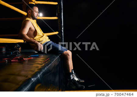 Tired boxer sitting on the side of the ring Tired boxer sitting on the side of the ring 70047464