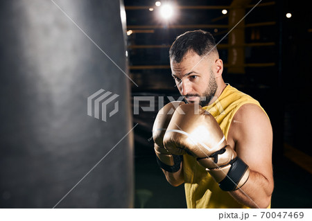 Boxer is training with heavy punch bag 70047469