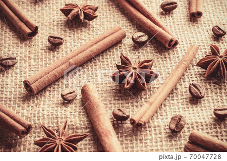 Coffee beans and cinnamon sticks with anise stars organized separately on sackcloth Coffee beans and cinnamon sticks with anise stars organized separately on sackcloth 70047728