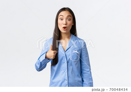 Impressed beautiful asian girl in blue pajamas showing thumbs-up and look amazed with great sleepover, awesome skincare product or promo. Woman showing support, recommend amazing thing Impressed beautiful asian girl in blue pajamas showing thumbs-up and look amazed with great sleepover, awesome skincare product or promo. Woman showing support, recommend amazing thing 70048434
