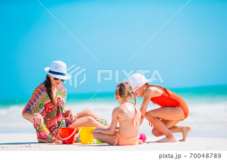 Family of four making sand castle at tropical white beach Family of four making sand castle at tropical white beach 70048789