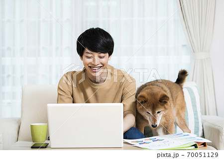 犬にテレワークを邪魔される若い男性の写真素材