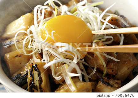 炭火で焼いた焼き鳥の上に白髪葱と卵黄を乗せた熱々ヤキトリ丼の黄身を箸で割って食べる 70056476