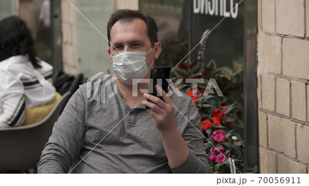 Man in a medical mask talking on a mobile phone using a modern messenger for video communication Man in a medical mask talking on a mobile phone using a modern messenger for video communication 70056911
