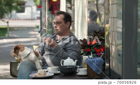 Man stroking a small dog lying in his lap Man stroking a small dog lying in his lap 70056926