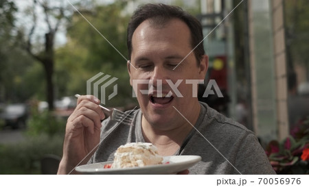 Man eating meringue roll Man eating meringue roll 70056976