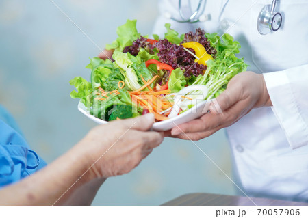 Asian senior or elderly old lady woman patient eating breakfast vegetable healthy food with hope and happy while sitting and hungry on bed in hospital. 70057906