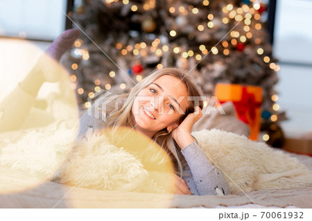 Dreamful cute teen girl near Christmas tree. Kid wearing pajama dreaming near tree in the morning. 70061932