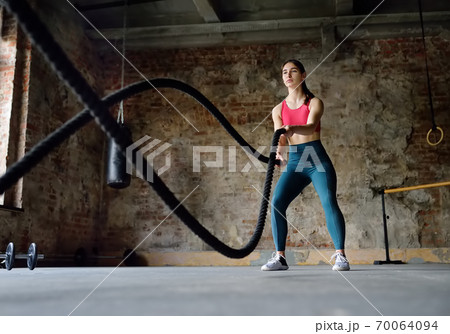 Young woman exercising with battle ropes at the gym. Young woman exercising with battle ropes at the gym. 70064094