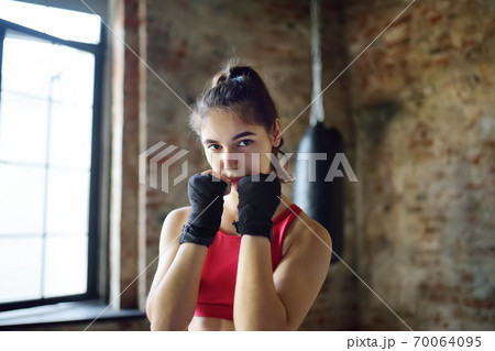 Young woman ready for hits punching bag during a boxing training. Female boxer doing fitness. Young woman ready for hits punching bag during a boxing training. Female boxer doing fitness. 70064095