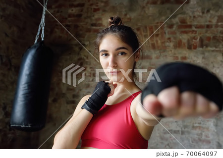 Young woman ready for hits punching bag during a boxing training. Female boxer doing fitness. 70064097