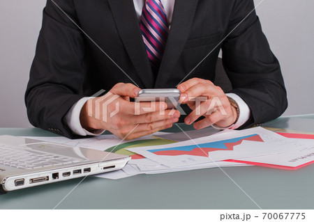 Man using smartphone sitting at office table. Man using smartphone sitting at office table. 70067775