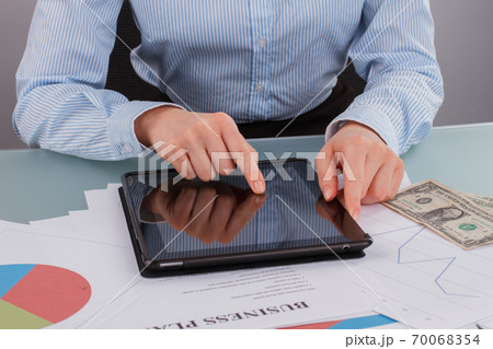 Hands of woman using pc tablet on table with documents. Hands of woman using pc tablet on table with documents. 70068354