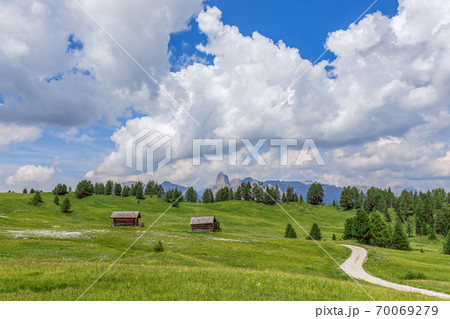 Rural road in green alpine valley with view of Italian Dolomites. Italian Alps, Corvara in Badia. Rural road in green alpine valley with view of Italian Dolomites. Italian Alps, Corvara in Badia. 70069279