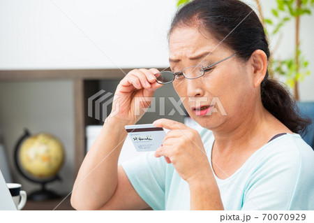 老眼鏡でカードを見るシニア女性 70070929