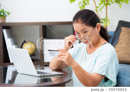 老眼鏡でカードを見るシニア女性 老眼鏡でカードを見るシニア女性 70070933