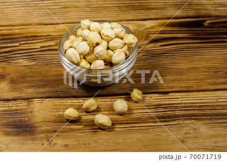 Peeled hazelnuts in glass bowl on wooden table Peeled hazelnuts in glass bowl on wooden table 70071719