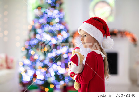 Little girl opening Christmas presents at fire place Little girl opening Christmas presents at fire place 70073140