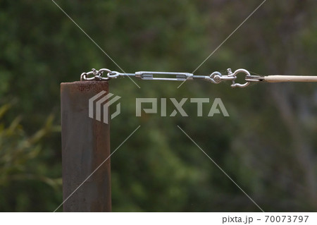 A stainless steel turnbuckle shackle connected to a black metal pole A stainless steel turnbuckle shackle connected to a black metal pole 70073797