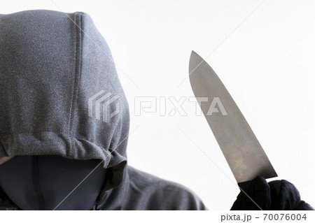包丁を持ち 顔を隠した怪しい男性の写真素材