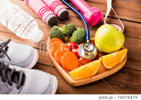 fresh organic fruits and vegetables in heart plate wood and sports equipment and doctor stethoscope fresh organic fruits and vegetables in heart plate wood and sports equipment and doctor stethoscope 70076879