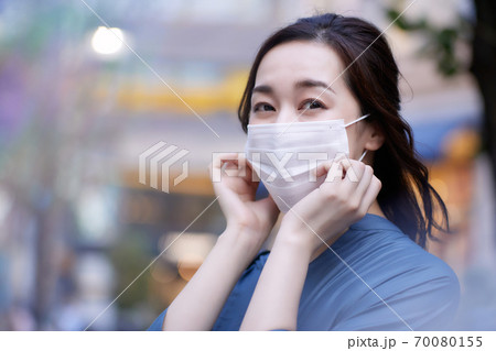 夕暮れ時の街に佇むマスクをした女性 ポートレート 夕暮れ時の街に佇むマスクをした女性 ポートレート 70080155