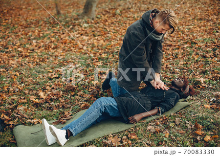 Man in a autumn park help african girl 70083330