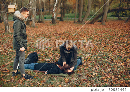 Two boys in a autumn park help a african girl Two boys in a autumn park help a african girl 70083445