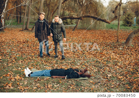 Two boys in a autumn park help a african girl 70083450