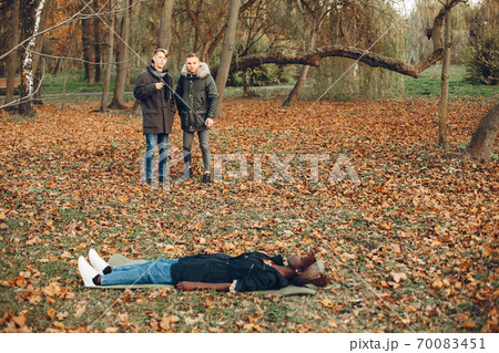 Two boys in a autumn park help a african girl 70083451