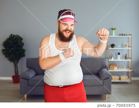 Funny fat boxer in sportswear is boxing in the room. 70083975