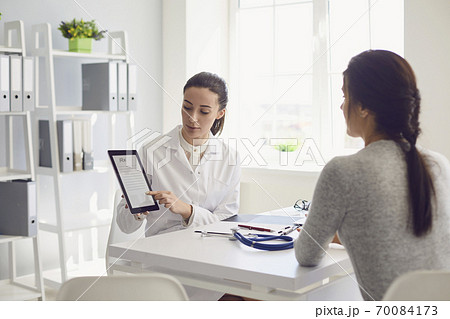 Woman patient visiting female doctor at clinic office. Medical work writes a prescription on a table in a hospital. 70084173