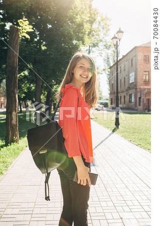 teenage girl with backpack strolling around city 70084430
