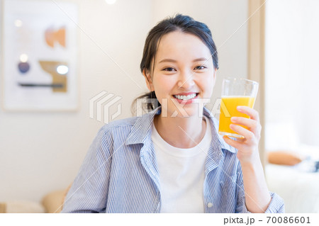 自宅でオレンジジュースを飲む若い女性 自宅でオレンジジュースを飲む若い女性 70086601
