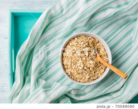 Oatmeal flakes in bowl on green napkin 70088080