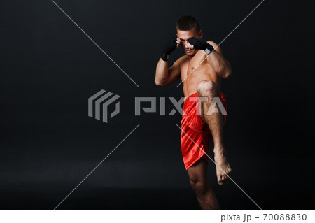 Sportsman muay thai man boxer stance ad knee kick at black background 70088830