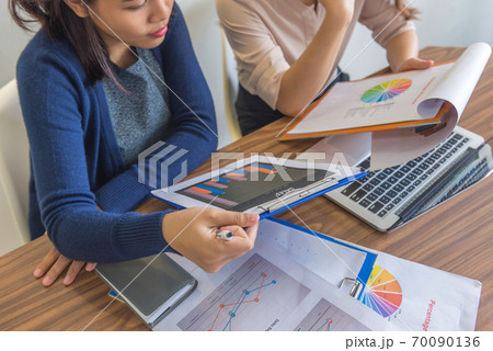 High angle view of businesswomen working on financial statistics documents 70090136