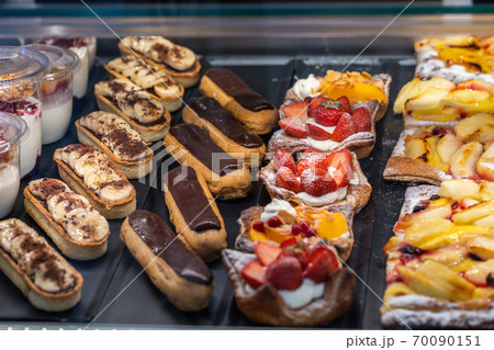 Delicious puffy chocolate eclair and strawberry tart in patisserie store 70090151