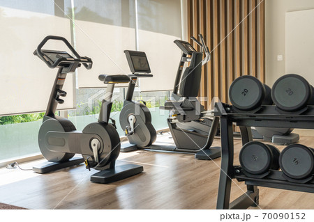 Sport bike and dumbbells in fitness room Sport bike and dumbbells in fitness room 70090152