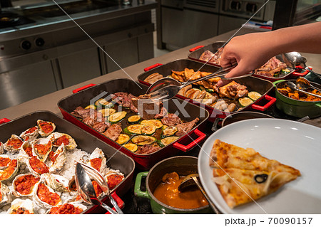 Human hand picking assorted food in luxury buffet meal Human hand picking assorted food in luxury buffet meal 70090157