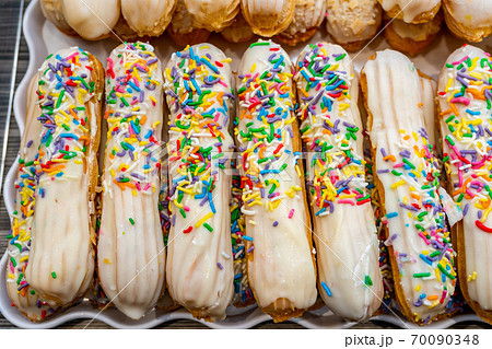 Pile of choux sticks pastry topped with colorful candy sprinkles 70090348
