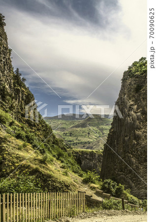Hills and the medieval bridge over the Azat river in Garni gorge among the bushes and green grass against the blue sky covered with clouds 70090625
