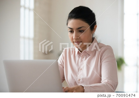 Young indian woman look at laptop screen working Young indian woman look at laptop screen working 70091474
