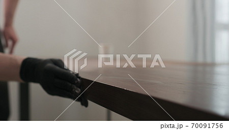 man hand applying oil finish to toned walnut table with cloth 70091756