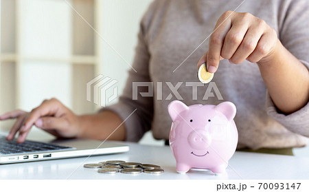 Young business women are saving money in a piggy bank and recording financial income-expenditures to prepare investments in real estate, Tax deduction and cost calculation concept. 70093147