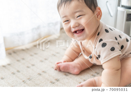 窓辺で笑顔でお座りをする赤ちゃん 70095031