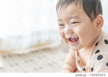 窓辺で笑顔でお座りをする赤ちゃん 窓辺で笑顔でお座りをする赤ちゃん 70095034